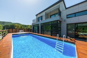 Un edificio moderno con piscina, ventanas amplias y zona de terraza.
