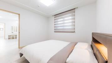 Ein modernes Schlafzimmer mit Bett, Nachttisch, Fenster mit Jalousien und Deckenleuchte.