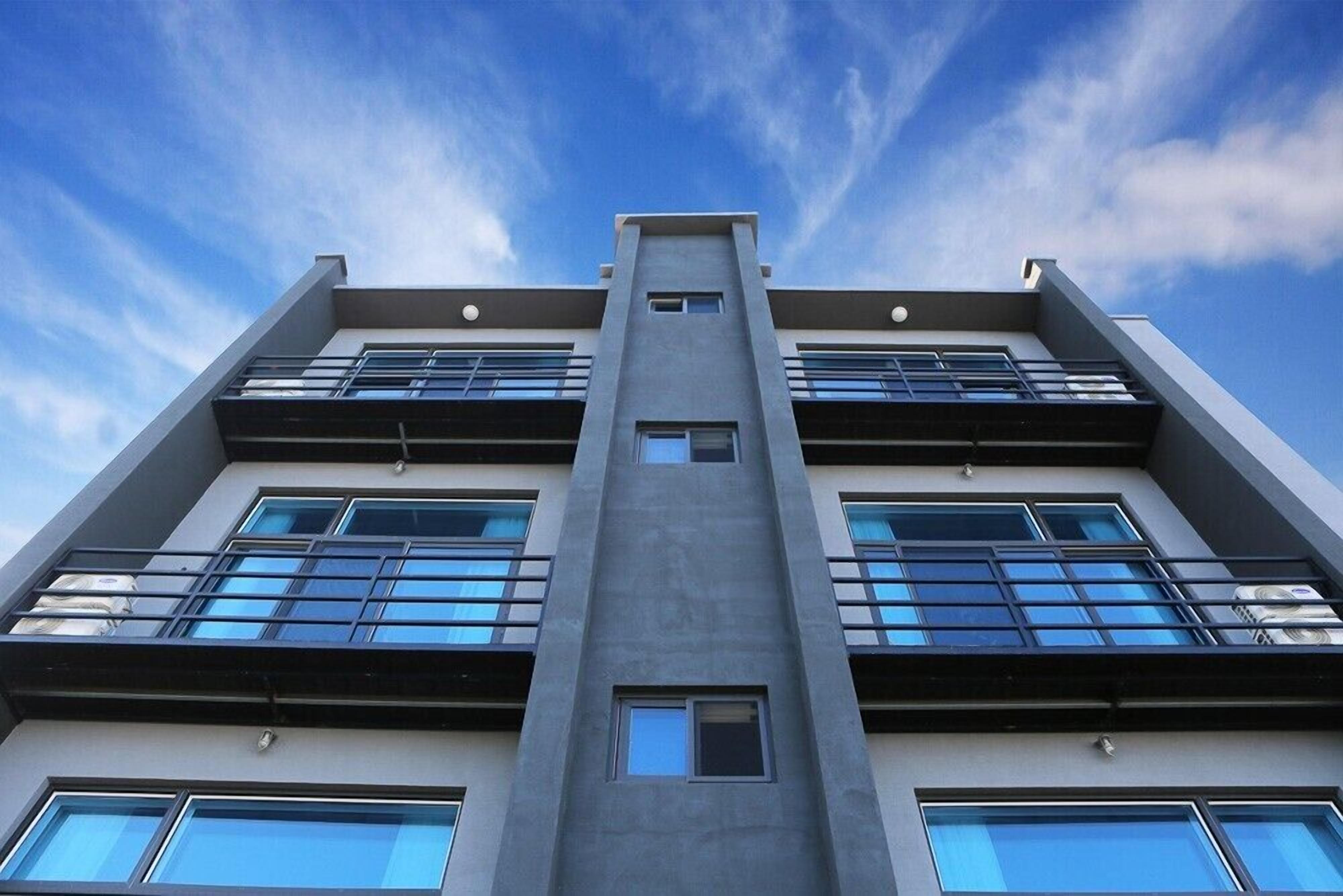 Un immeuble moderne à plusieurs étages, doté de grandes fenêtres et d’une structure verticale centrale.