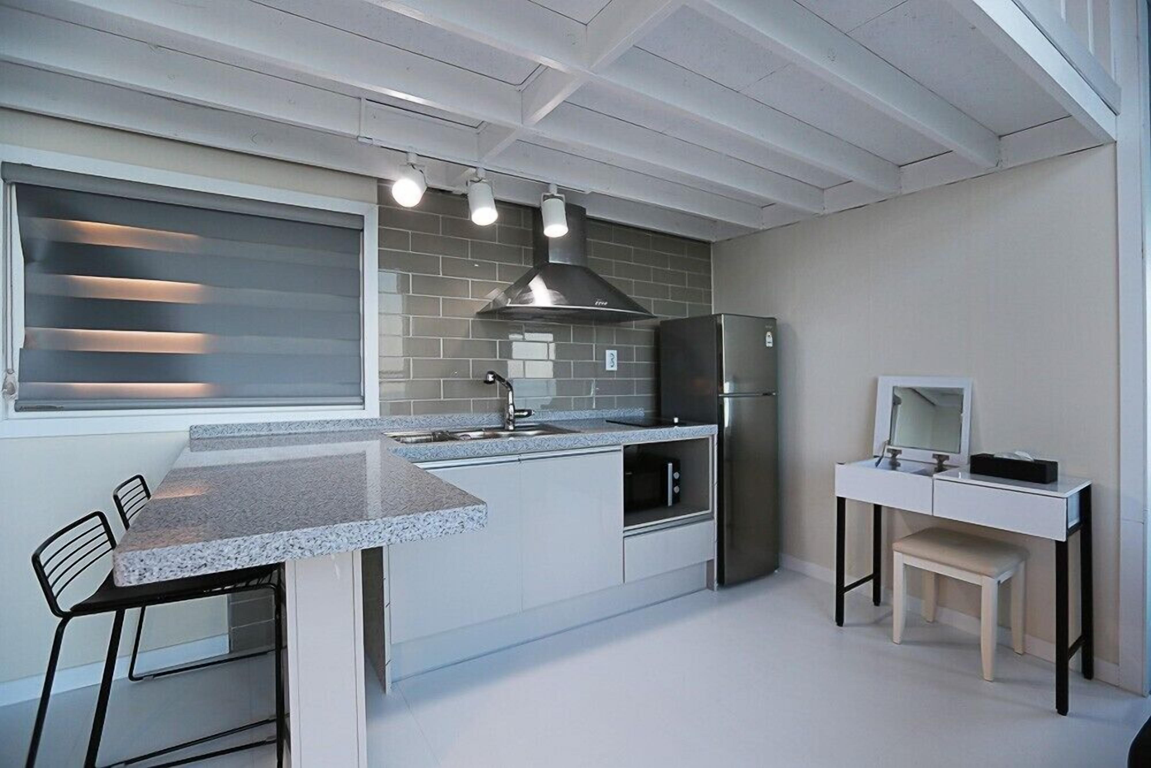 Una cocina moderna con encimera de granito, electrodomésticos de acero inoxidable y diseño de muebles blancos.