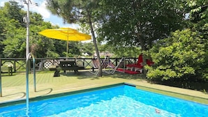 A swimming pool with a wooden deck, picnic table, and hammock chairs. - Herb Story Pension (Chuncheon)