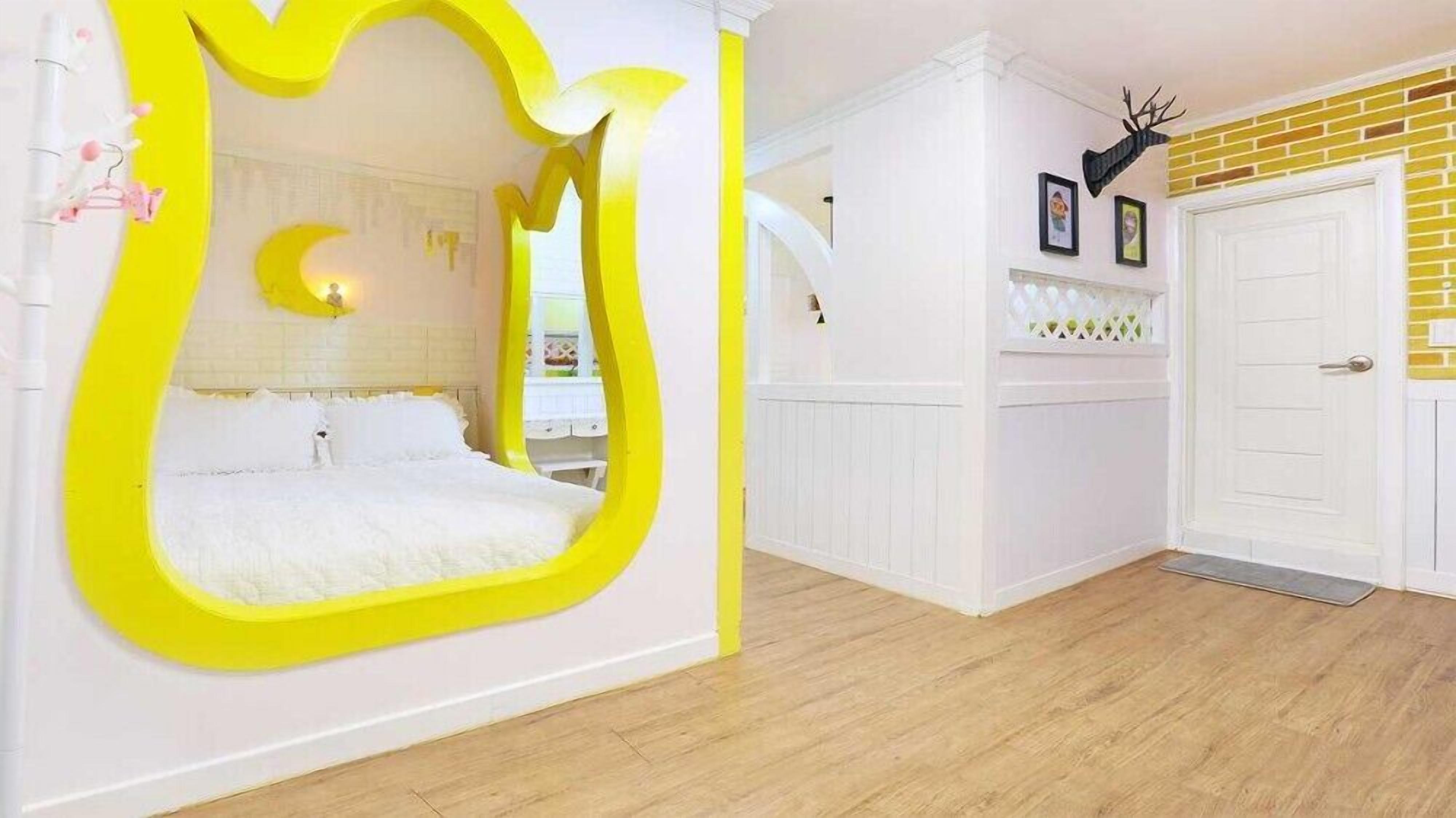 A bedroom with a large mirror, a bed, a white door, and a brick wall.