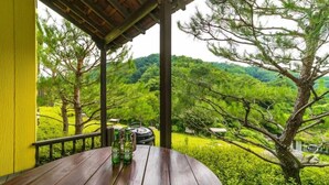 A wooden table with bottles on a balcony overlooking a lush green landscape. - Yangpyung Lavin Pension (Yangpyeong)