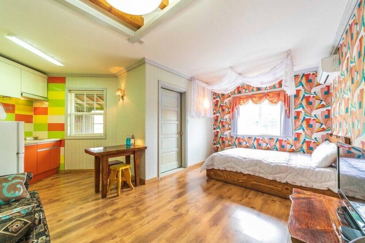 A compact room with a bed, a small table, and a kitchenette.