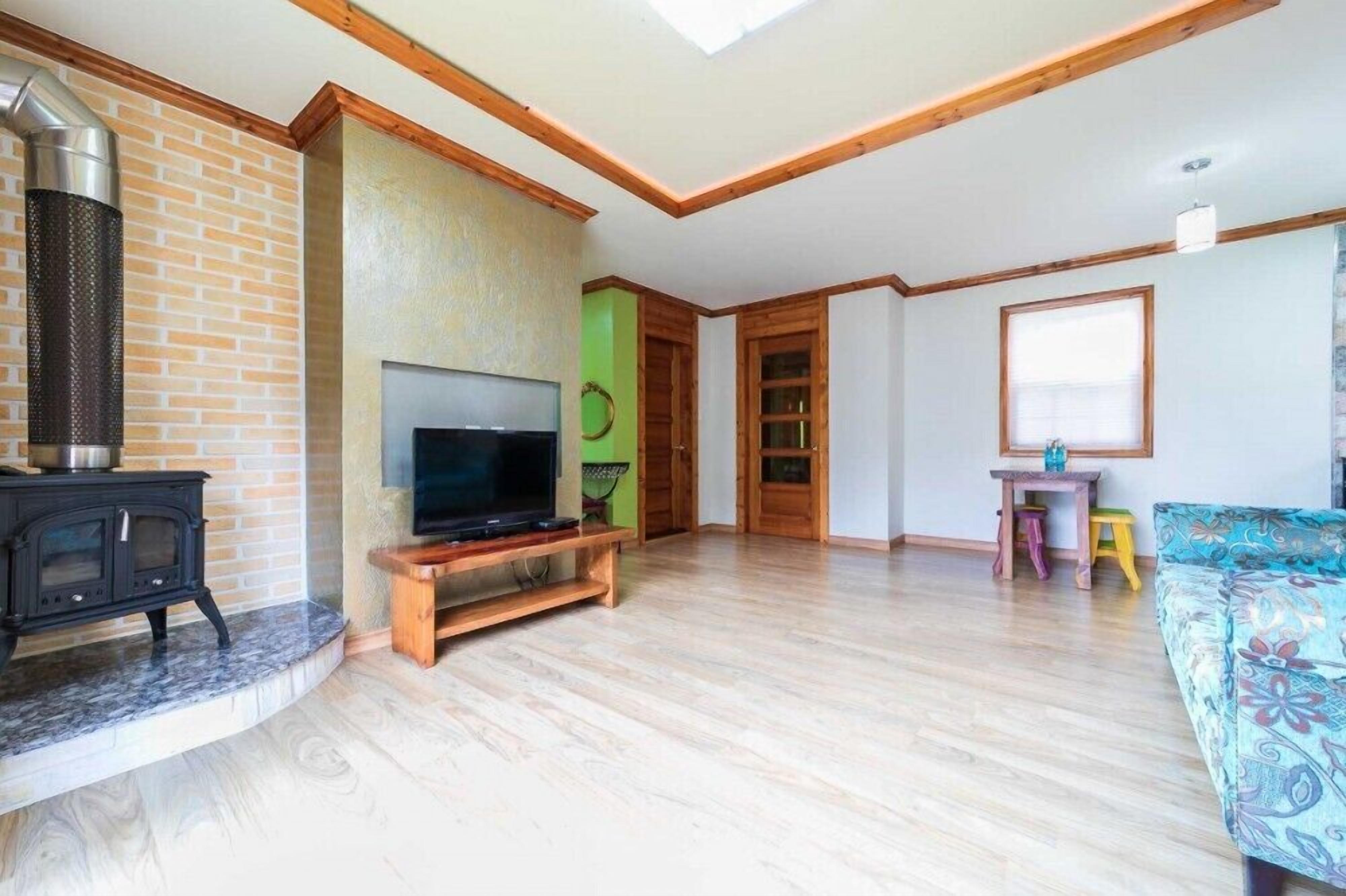 A living room with a fireplace, TV, wooden furniture, and a sofa.