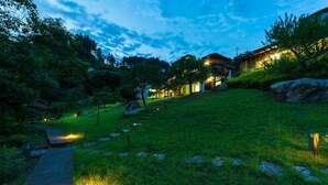 A pathway leading to a house with a wooden deck and a grassy area with rocks. - Yangpyung Lavin Pension (Yangpyeong)