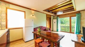 Eine Küche mit einem Holztisch, zwei Hocker, einem Kühlschrank und einer Couch.