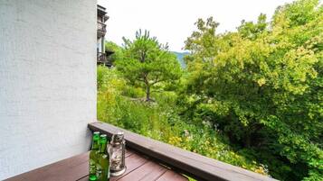 A balcony with a wooden table, two green bottles, and a glass bottle.