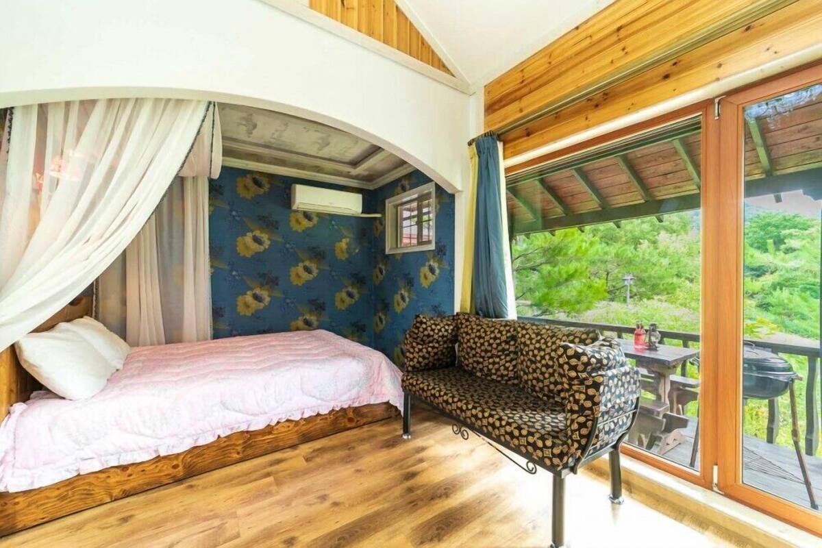 A bedroom with a bed, a sofa, and a large window.