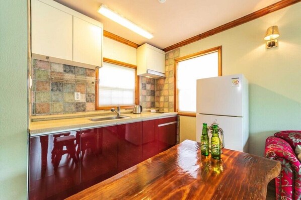 A compact kitchen with a wooden table, a refrigerator, and a window. - Yangpyung Lavin Pension (Yangpyeong)