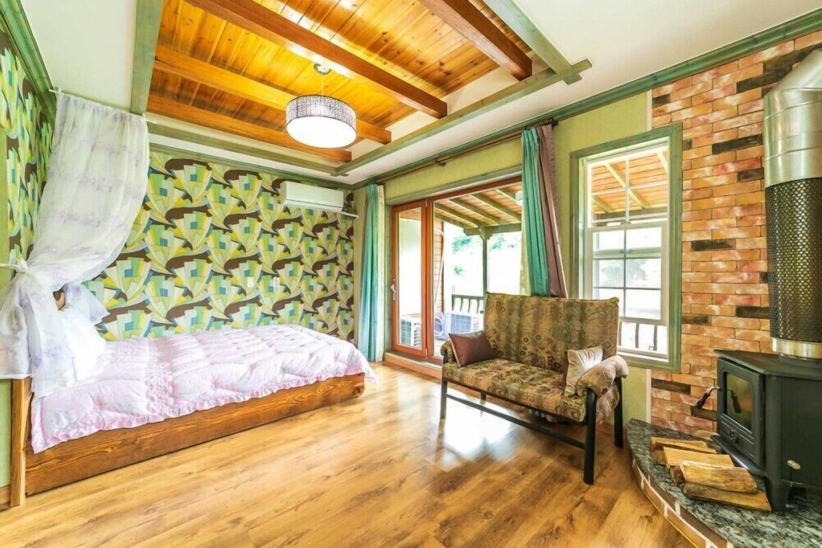 A cozy room with a bed, a chair, a fireplace, and a patterned wall.
