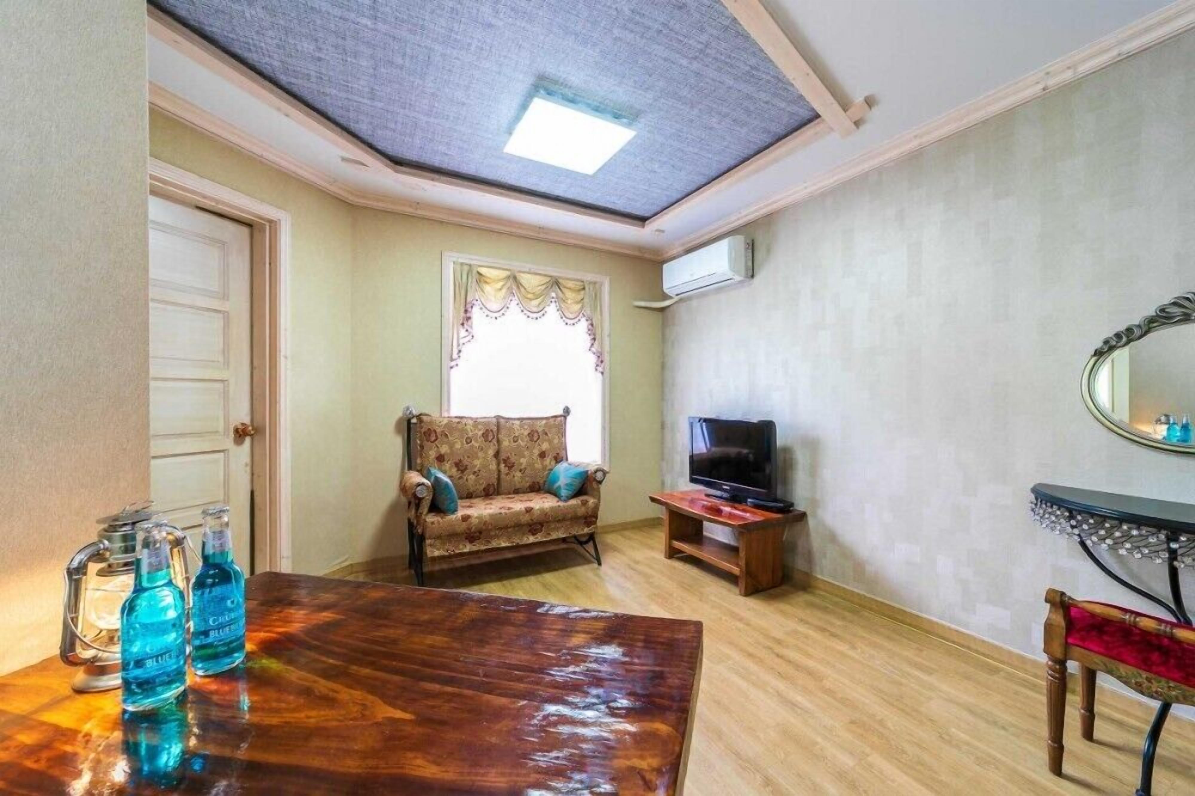A living room with a sofa, a TV, a wooden table, and a mirror.