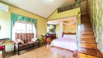 Una habitación con sofá, cama, escalera y zona de cocina.