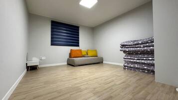 Una habitación con un sofá gris, una ventana con persianas horizontales y un conjunto de ropa de cama con estampado de estrellas.
