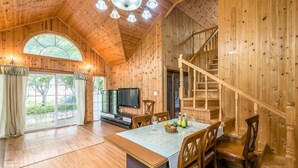 Un interior de madera con comedor, televisor y escalera.