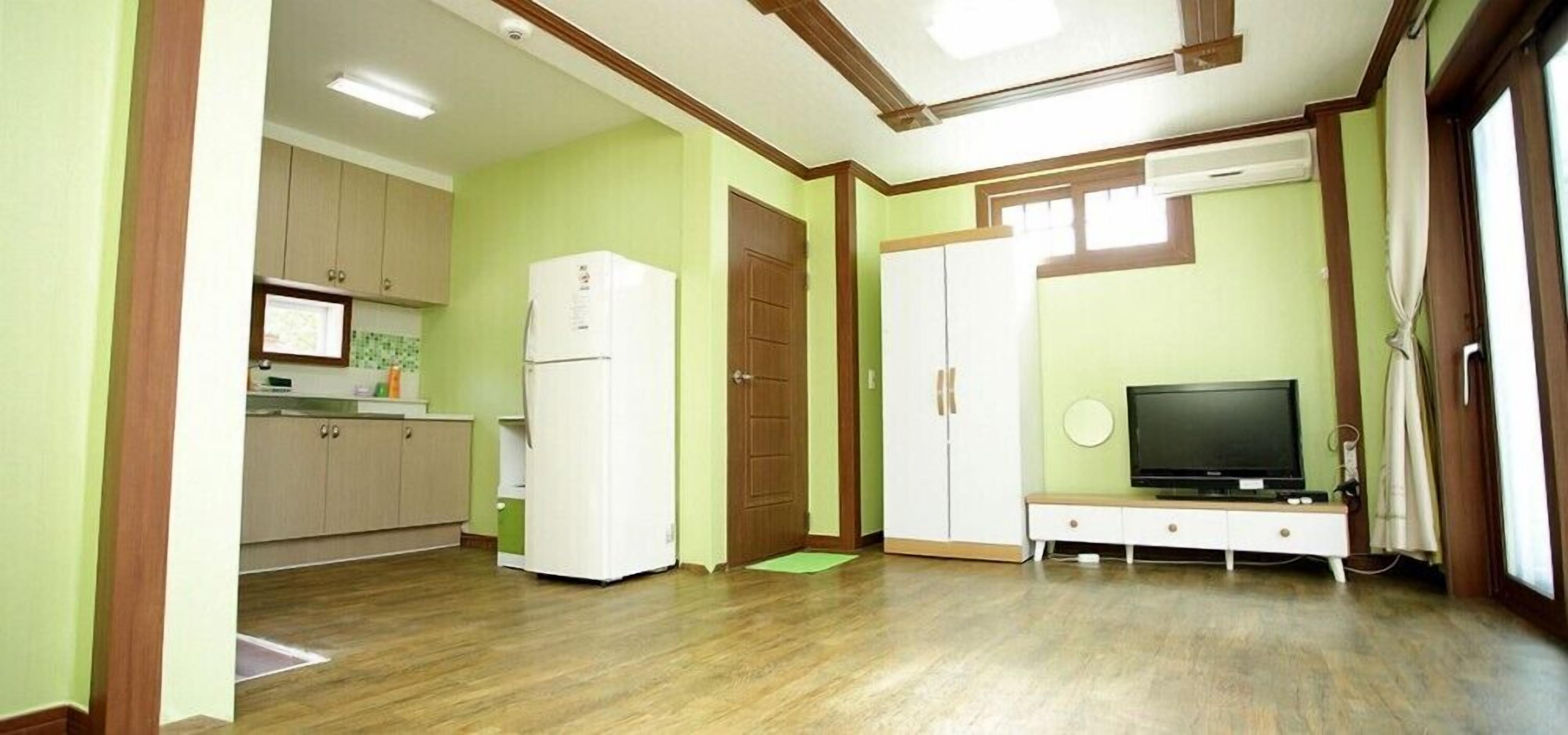 A compact living space with a kitchenette, a television, and a door leading to another room.