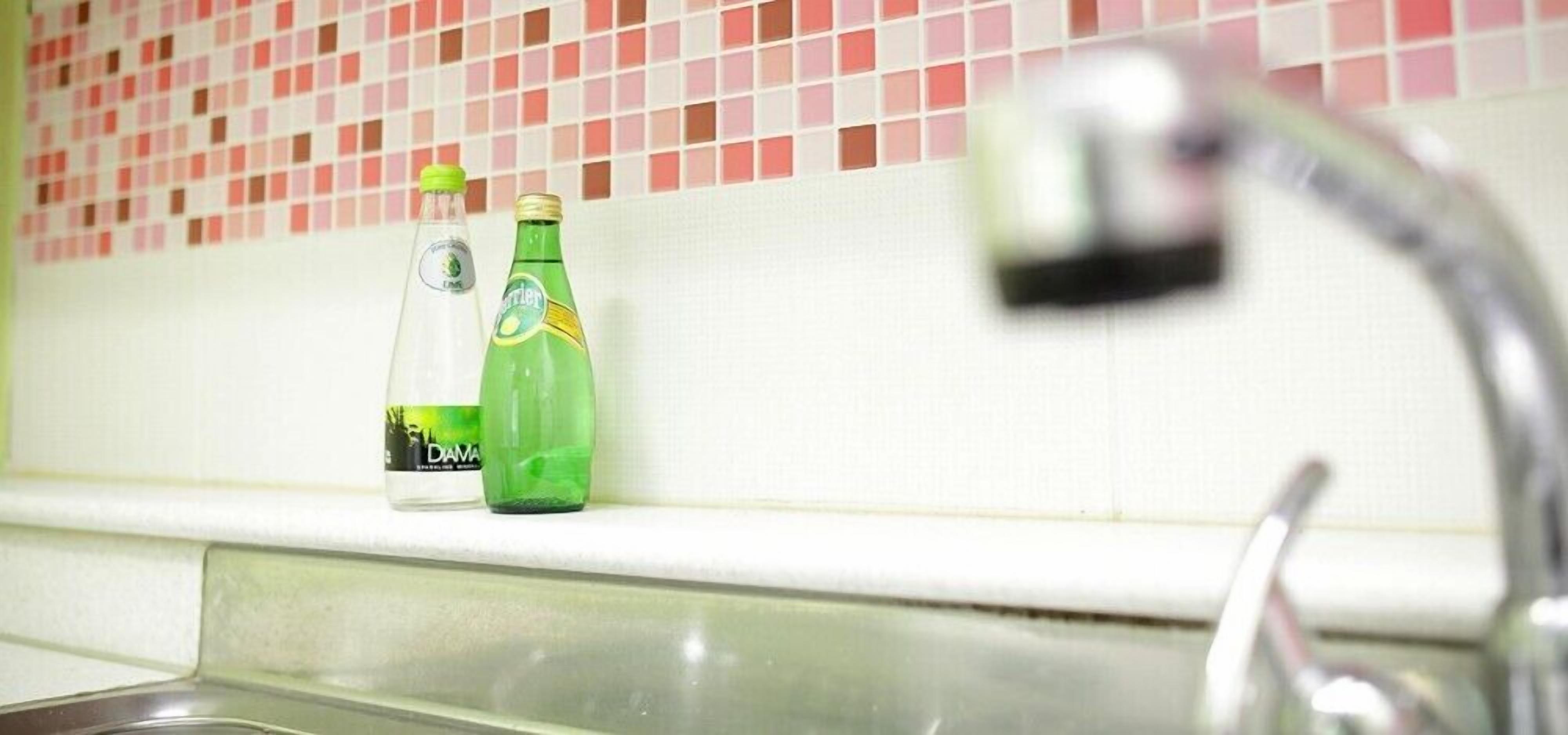 Ein Küchenspüle mit zwei Soflaschen und einem Wasserhahn.