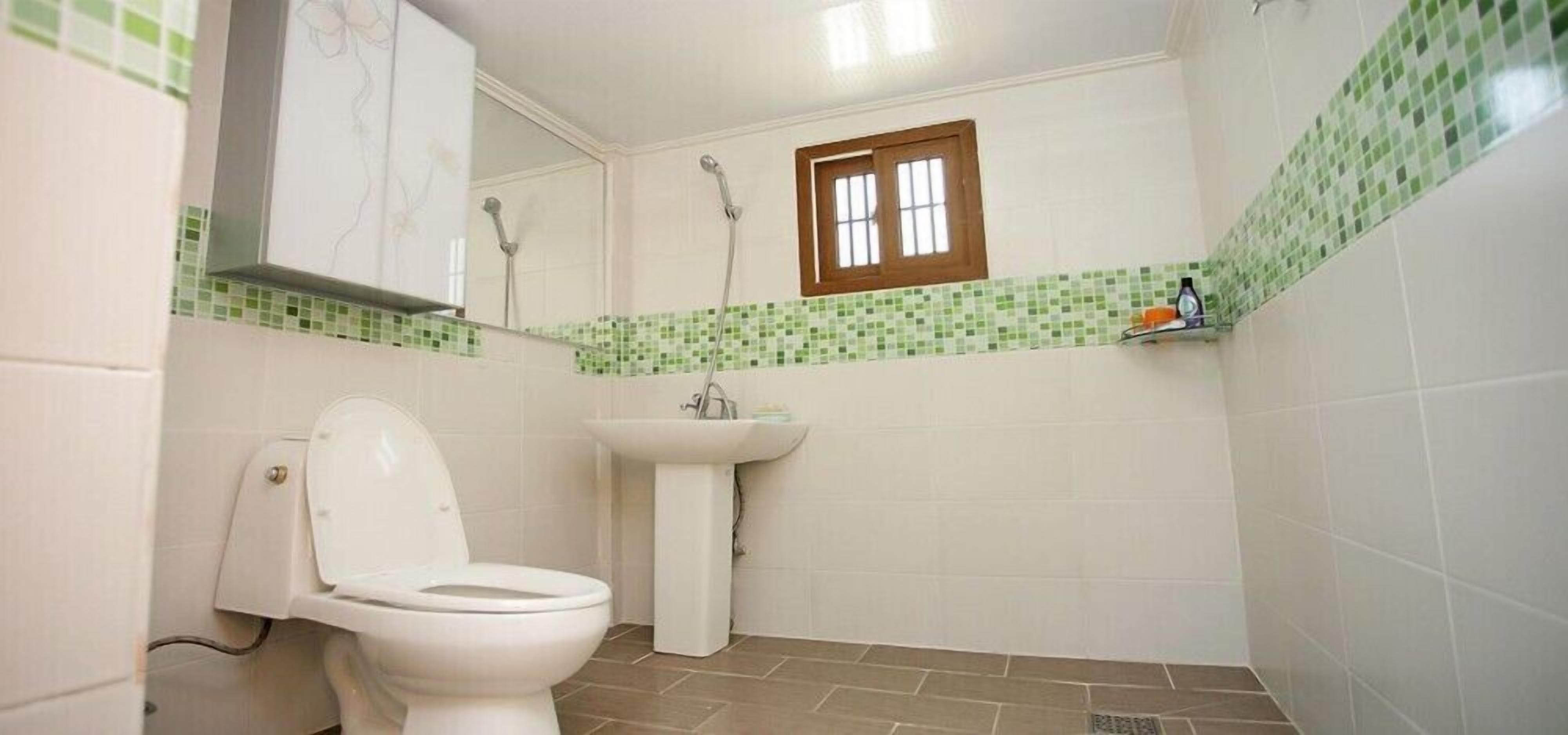 A small bathroom with a toilet, sink, and shower.