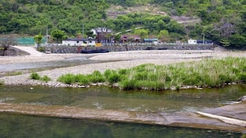 A river with a small bridge, a grassy area, and buildings in the background.
