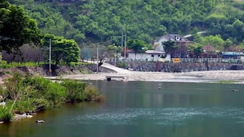 Vistes al riu amb un pont, una casa i un mur de pedra.