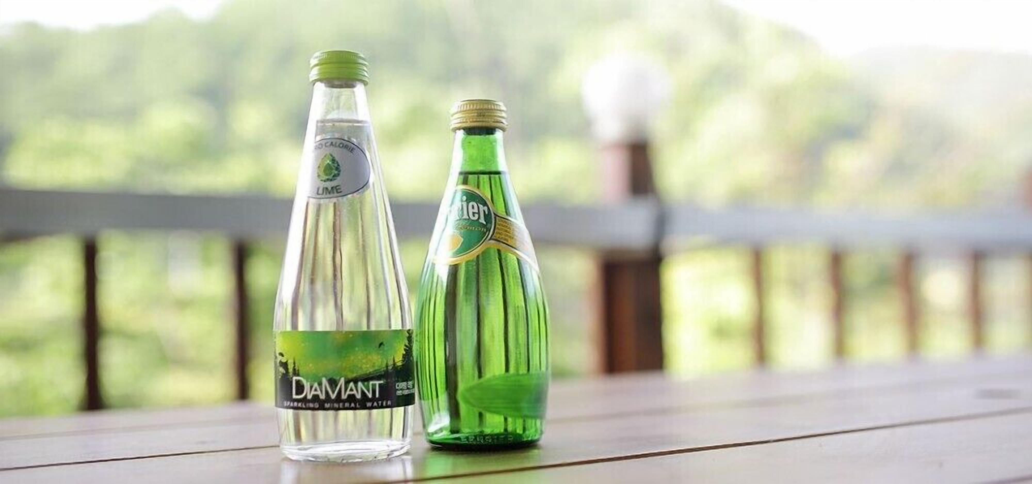 Two bottles of water on a wooden surface with a blurred natural background.