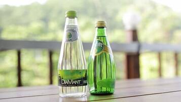 Two bottles of water on a wooden surface with a blurred natural background.
