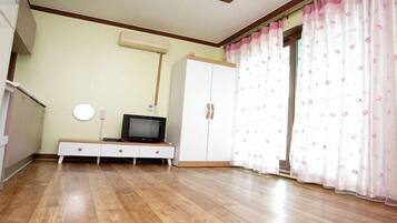 A room with a TV on a stand, a wardrobe, and a curtain with a floral pattern.