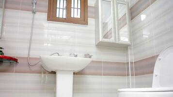 A bathroom with a white sink, a toilet, and a shower.