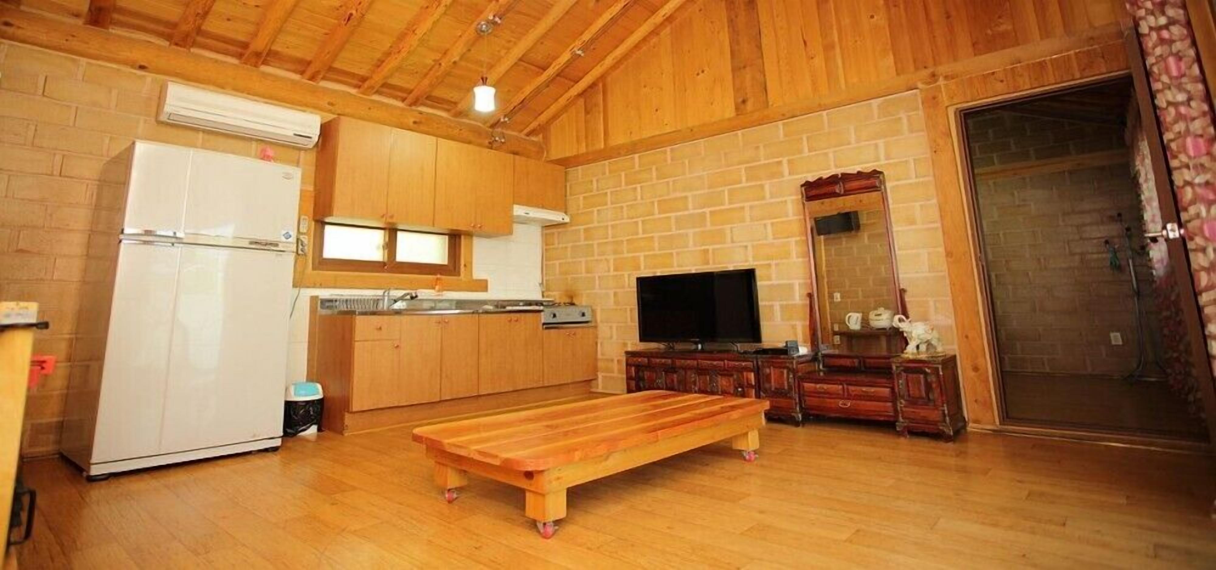 Een houten interieur met een keuken, een televisie en een bank.