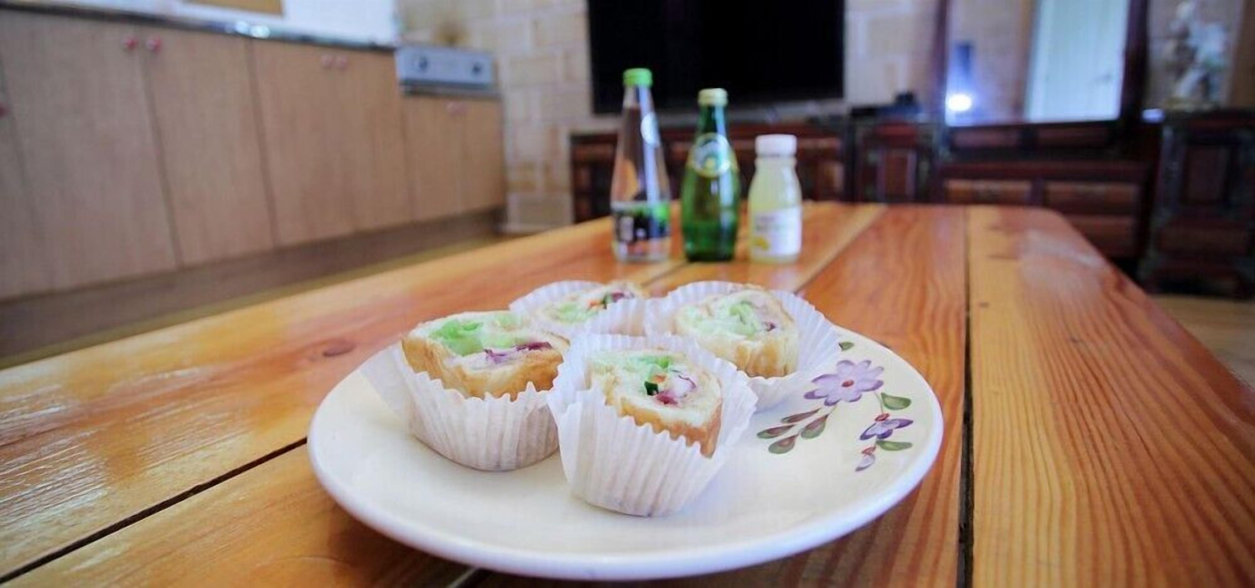 A plate of food on a wooden table with bottles in the background.
