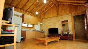 A rustic wooden interior with a kitchen, a TV, and a bench. - Bandi Hwangto Pension (Miryang)
