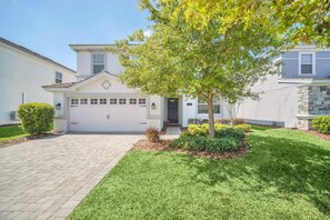 A two-story house with a garage, a well-maintained lawn, and a tree in the front yard.
