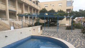 Una piscina amb un videtatge de rajola, una escala que condueix a un balcó, i un edifici al fons amb diversos balcons.