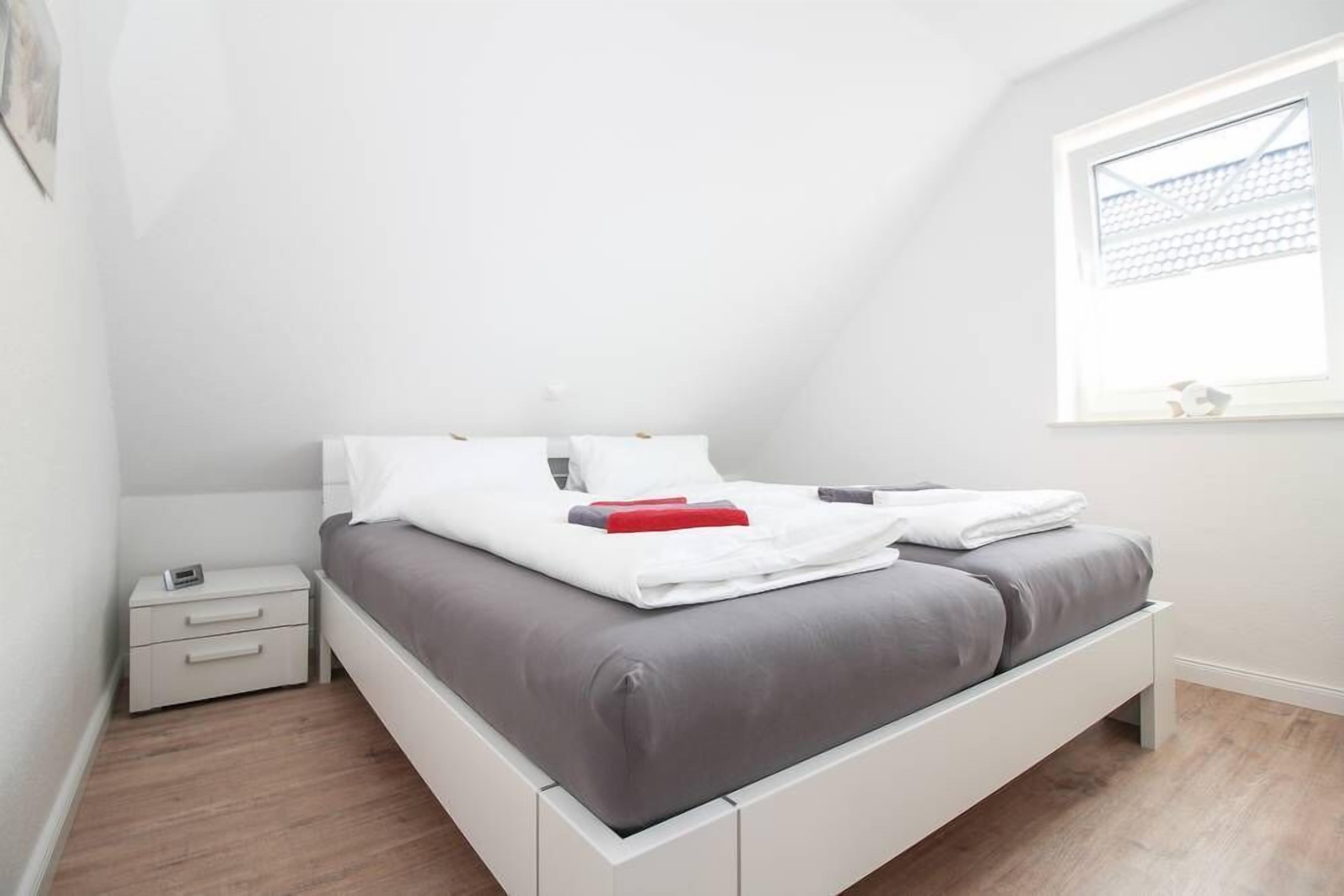 A modern bedroom with a bed, nightstand, and a window with blinds.