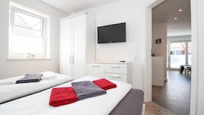 Una habitación de hotel con dos camas, un televisor de pantalla plana y una ventana.