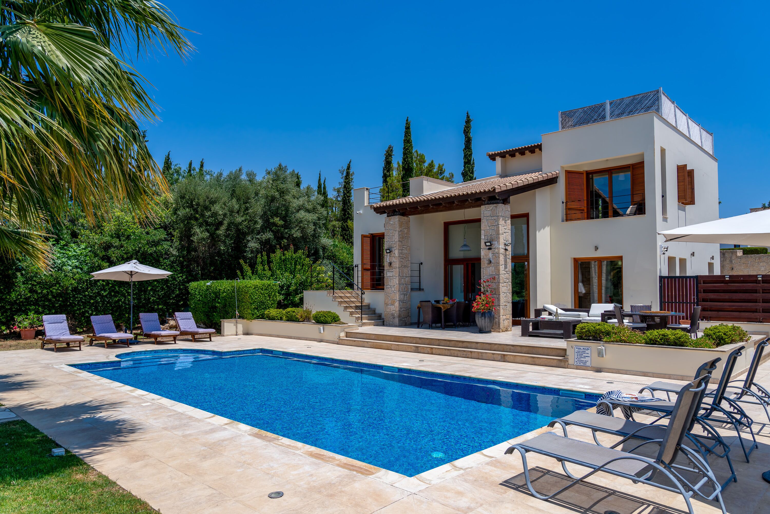 A modern house with a swimming pool, outdoor seating, and a well-maintained garden.