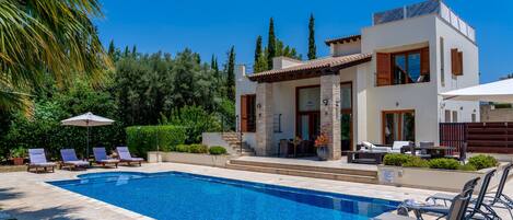 A modern house with a swimming pool, outdoor seating, and a well-maintained garden.