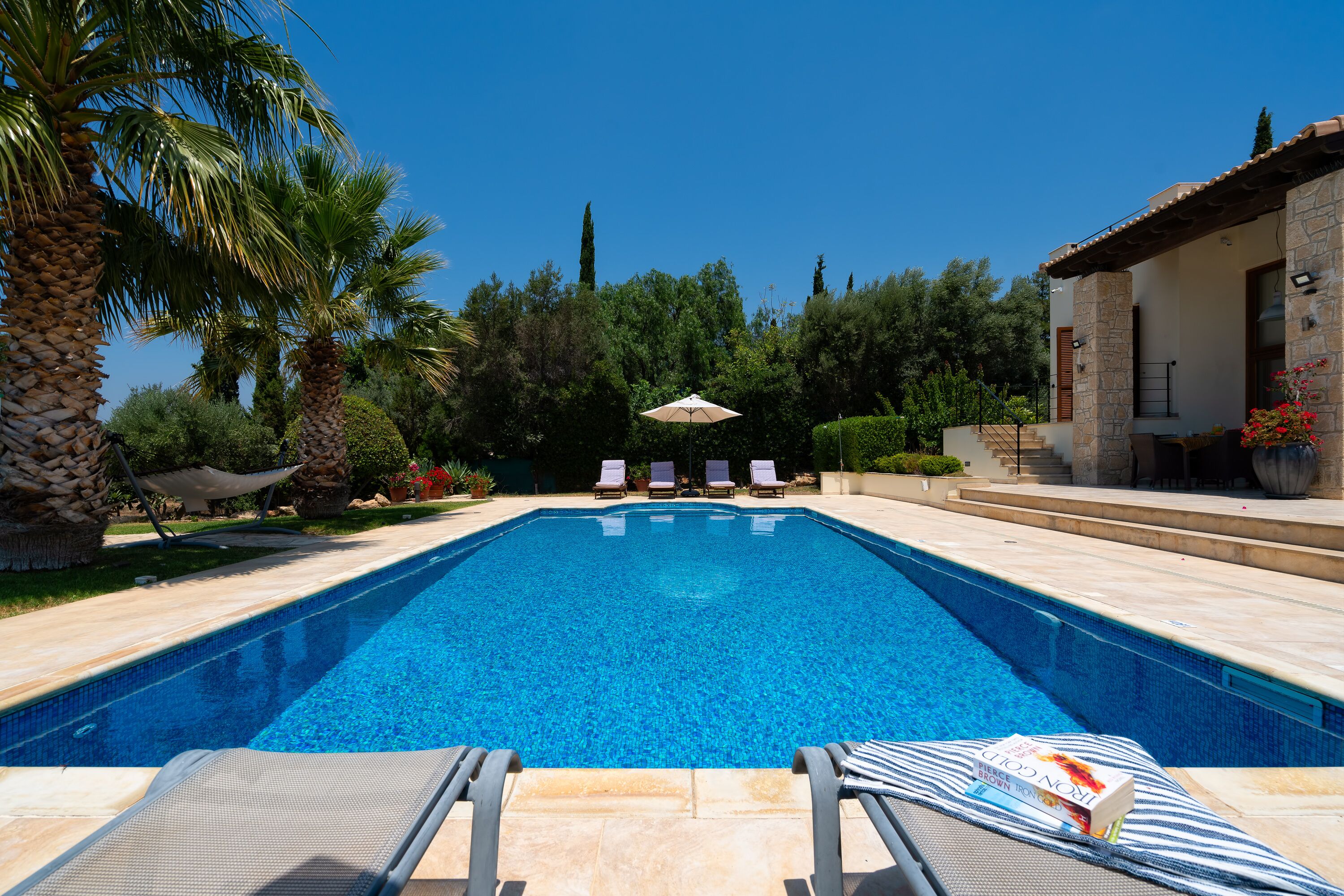 A swimming pool with lounge chairs and a book on one of the chairs.