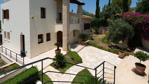 A modern two-story building with a stone facade, a covered outdoor area with potted plants, and a stone pathway leading to the entrance. - Villa 148 - Lofou (Kouklia)