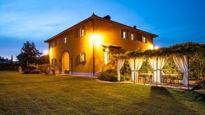A large, two-story house with a well-maintained lawn and a patio area with a table and chairs.