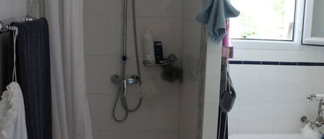 Ein Badezimmer mit Dusche, Badewanne und Fenster.