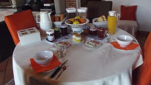 A breakfast table set with various food items, a coffee pot, and a fruit basket. - Entre Terre et Mer (Saint-Jean-de-Monts)