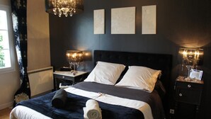 A hotel room with a large bed, two bedside lamps, a chandelier, and artwork on the wall. - Entre Terre et Mer (Saint-Jean-de-Monts)