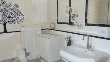 Een badkamer met een wit wastafelmeubel, een spiegel en een klok aan de muur.
