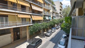 A multi-story residential building with balconies, parked cars, and a sidewalk. - Check Point - Veikou (Athens)