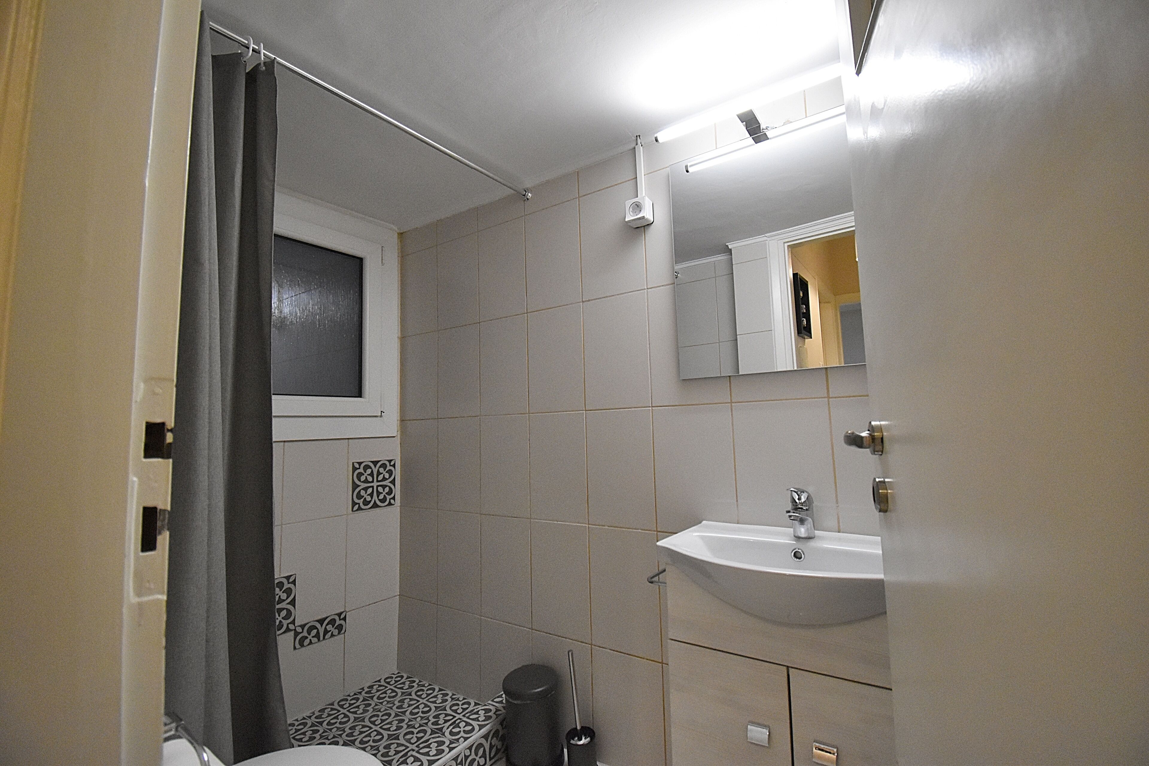 A bathroom with a toilet, sink, and window.