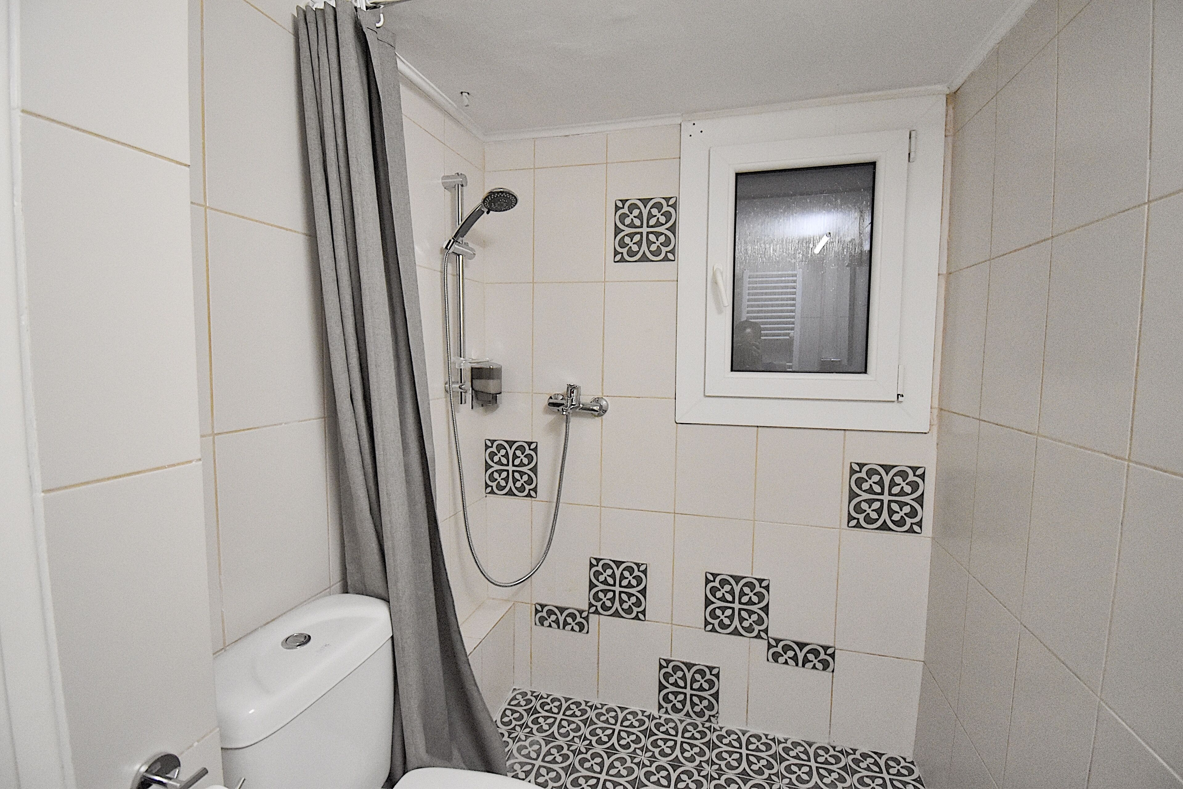 Ein kleines Badezimmer mit Toilette, Dusche und einem Fenster.