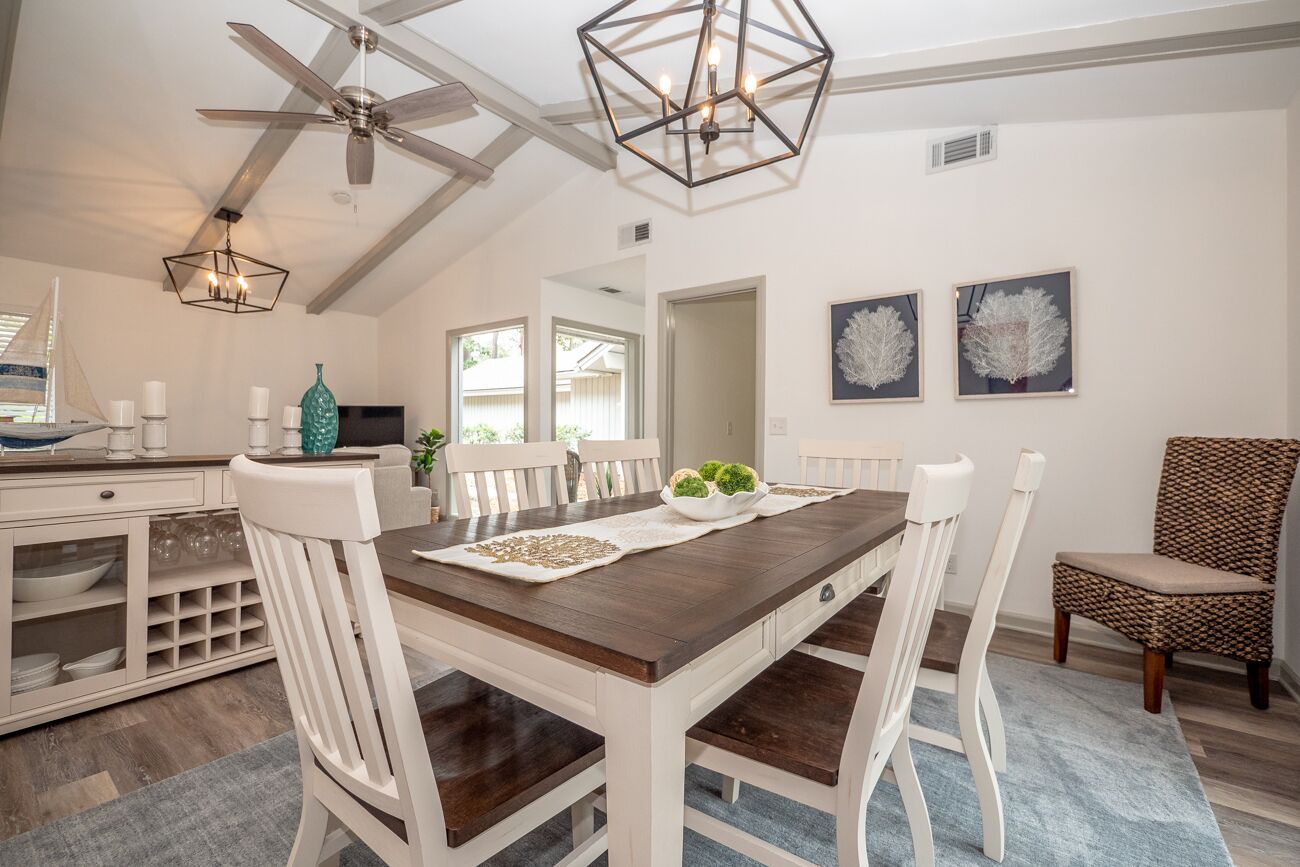 A dining area with a wooden table, white chairs, and a ceiling fan.
