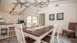 A dining area with a wooden table, white chairs, and a ceiling fan. - 55 Lawton: Pet Friendly, Modern Luxury, Remodeled Sea Pines Home. Free Bikes (Hilton Head Island)