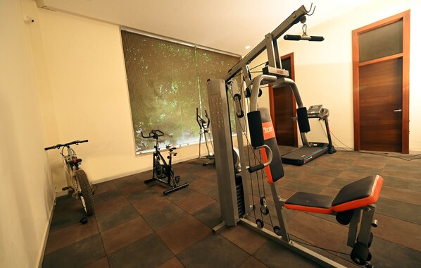 Un gimnasio en casa con cinta de correr, bicicleta estática y máquina de pesas.